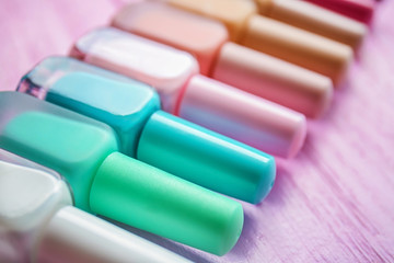 Bottles of colorful nail polishes on wooden background, closeup