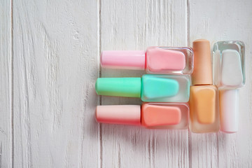 Bottles of colorful nail polishes on wooden background