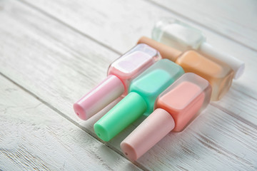 Bottles of colorful nail polishes on wooden background