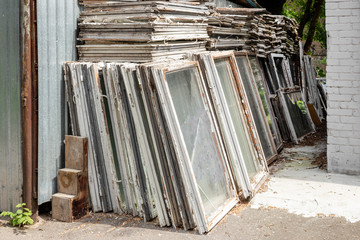 Heap of old wooden window frames with glass outdoors. Broken materials after window energy saving...