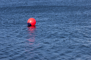 Rote Boje in blauem Wasser/ Markierung im Hafen