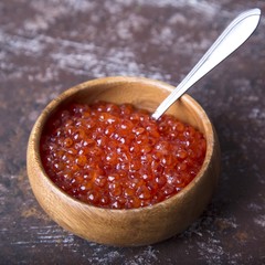 Red caviar in wooden bowl with spoon . Seafood. Diet.