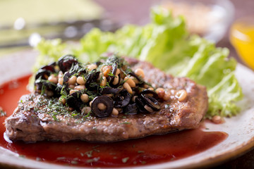 Tasty veal with pine nuts, olives in red wine with honey. Tasty dinner.  Closeup
