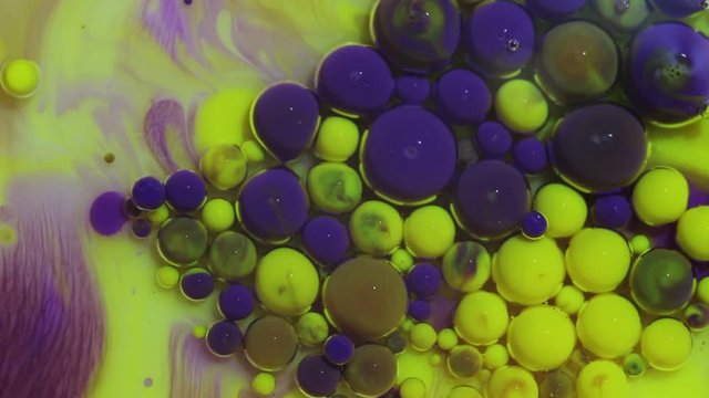 Abstract colorful background. Yellow and violet paint. Multicolored colorful ink bubbles moving underwater closeup