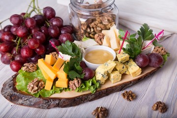 Cheese plate with nuts, grape  and honey. Cold appetizer