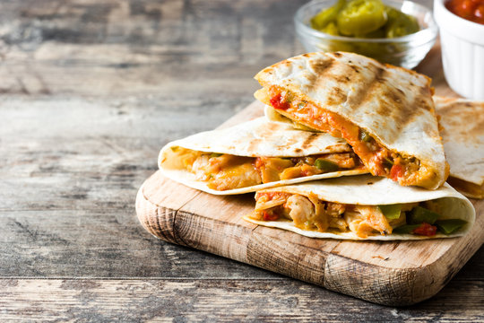 Mexican quesadilla with chicken, cheese and peppers on wooden table. Copyspace