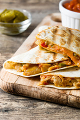 Mexican quesadilla with chicken, cheese and peppers on wooden table. 