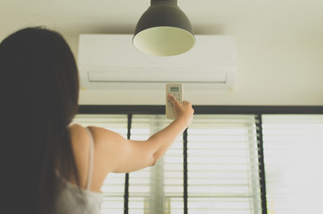 Hand using a remote control to activating air conditioning,Woman operating remote controller at home