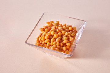 Yellow ripe sweet berries - sea buckthorn in the glass bowl on a beige paper background.
