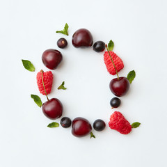 Colorful fruits pattern of letter Q english alphabet from natural ripe berries - black currant, cherries, raspberry, mint leaf isolated on a white background. Top view.