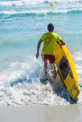 Lifeguard running in the sea with surfboard rescue