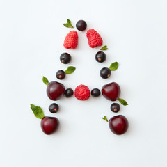 Naklejka na ściany i meble Berries pattern of letter A english alphabet from natural ripe berries - black currant, cherries, raspberry, mint leaf isolated on a white background.
