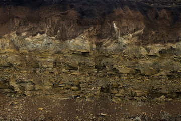 Soil cut-sandstone, stones, clay, sand structure and layers. slice of sand with layers of different...