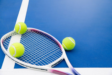 Tennis ball and tennis racket on a tennis court. Close up of tennis ball and tennis racket on hard court.