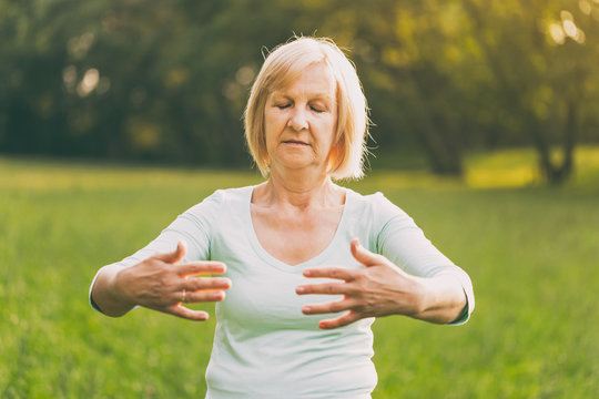 Senior woman enjoys  exercise Tai Chi in the nature.