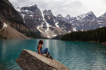 Fototapeta na wymiar Adventurous woman is enjoying the beautiful Canadian Rockies view. Taken in Moraine Lake, Banff National Park, Alberta, Canada.