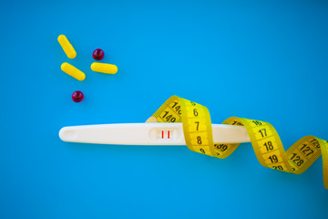 Pregnancy planning concep. Pregnancy test positive with two stripes and contraceptive pill on blue...