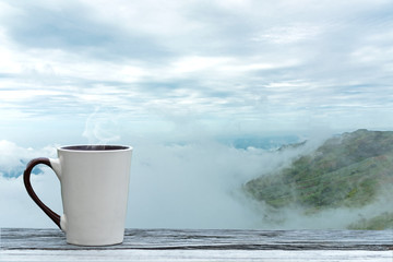 Cup coffee and tea with steam on wood table over mountains city landscape with mist sunlight winter.   Beauty nature background. Lifestyle Concept