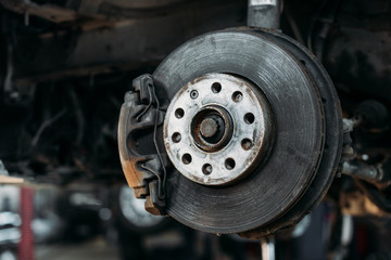 close up of car without wheel in mechanic shop