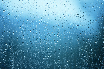 Rain drops on the glass window as background. Blue color tone used.