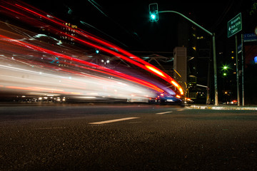 Wallpaper background of long exposure image at night of a car in the downtown streets with green traffic light.