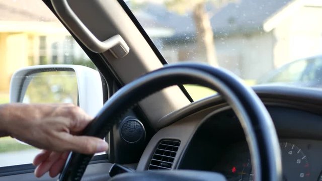 CLOSE UP A man's hands on steering wheel while driving a car.