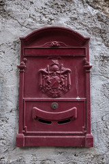 Vertical image of a mailbox with a wall in the background. No people.