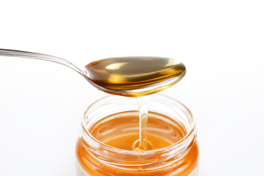 Jar of sweet honey with silver spoon on a white background. Health and beauty concept.