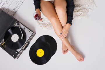 Woman drinking wine and listening to music on a record player and vinyl records