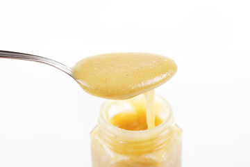 Jar of sweet honey with silver spoon on a white background. Health and beauty concept.