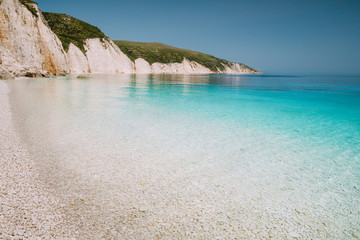 Fteri beach in Kefalonia Island, Greece. One of the most beautiful untouched pebble beach with pure azure emerald sea water surrounded by high white rocky cliffs of Kefalonia - obrazy, fototapety, plakaty