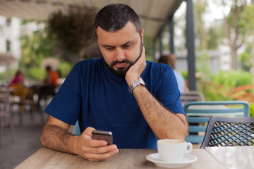 Worried man holding and using phone