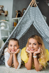 mother and daughter lying in teepee and looking at camera at home © LIGHTFIELD STUDIOS