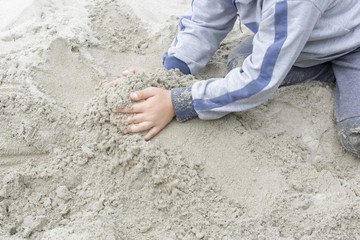 
Little boy playing in the sand with his toys