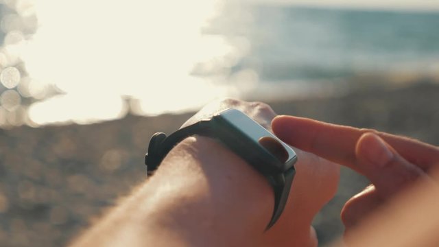 Close-up of a sports watch on a hand. Doing sports on the sea shore. The concept of a healthy lifestyle