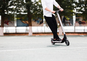Modern man in stylish black and white outfit riding electric scooter in the city © Leika production