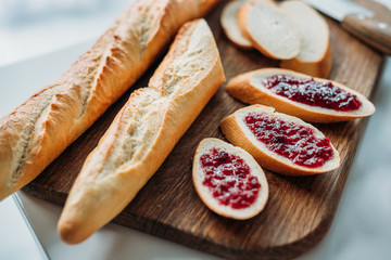 close-up shot of sliced baguette with jam on wooden cutting board