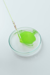 close-up shot of green liquid pouring from pipette into petri dish