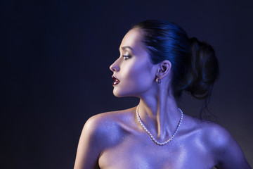 Beautiful brunette girl with naked shoulders and dark red lips make-up, wearing earrings and a...