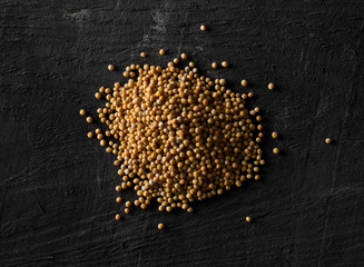 Heap of raw, unprocessed mustard seed kernels on black table