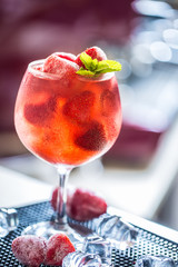 Strawberry lemonade or alcoholic cocktail with ice syrup soda and mint leaves on bar table