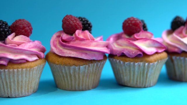 Delicious and appetizing capkake with a pink filling with two berries of blackberries and raspberries on a blue background. Four Cappey Cakes