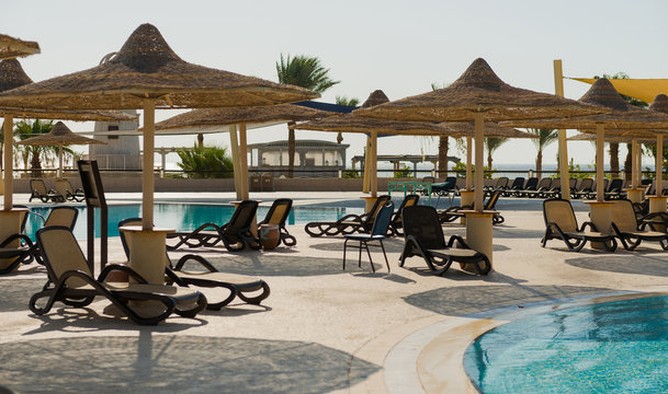 swimming pool and sunbeds at seasore background