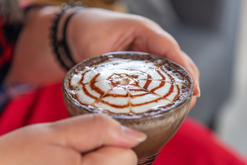 Hand women with cappuccino coffee in a cup blurred background