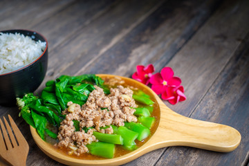 Stir fried Hong Kong kale with pork chops on a wooden table.