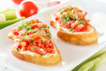 Bruschetta with fresh tomatoes and cheese on white boards next to fresh vegetables. Close-up