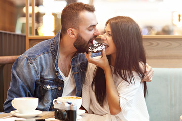Romantic couple dating in cafe and eating donut