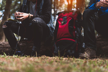 Traveler man backpacker using a smart phone in forest with sunlight