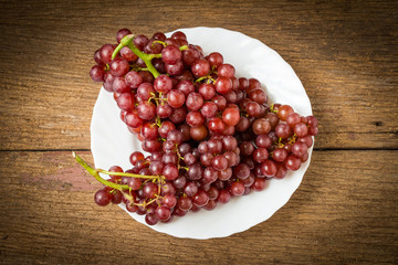 grapes seedless red on dish on old wood