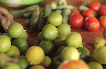 food macro background- many yellow and green limes  and a few tomatoes outdoors on a sunny day in Africa